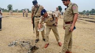 Efectivos de la policía india inspeccionan un objeto que se cree que formaría parte de un proyectil interceptado por el ejército en la localidad de Nahlan, a las afueras de Jalandhar, India, este sábado.